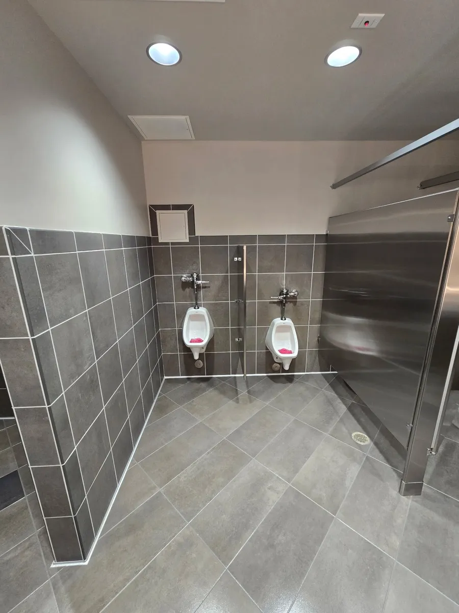 Gray restroom floor tile, grout joints, and fixture edges